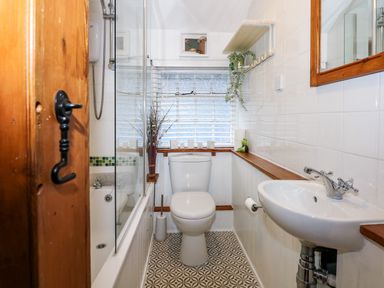 A bathroom with a toilet sink bathtub and window with blinds at Llety in Beddgelert