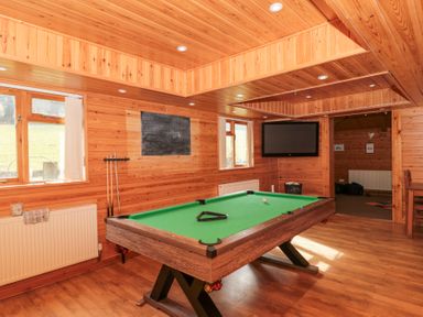 A room with wooden walls and ceiling containing a pool table two windows a television and a blackboard at Bell tent 2 in Camerton near Timsbury