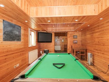 A wooden room with a pool table a blackboard television and a small dining table with chairs at Bell tent 2 in Camerton near Timsbury