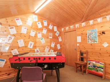 A room with a foosball table a chair a wooden wall with papers a Toy Story poster and a book rack at Bell tent 2 Camerton near Timsbury