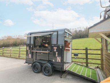 A black mobile trailer with a serving window and green carpeted ramp in a rural outdoor setting at Bell tent 2 in Camerton near Timsbury