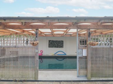 An indoor swimming pool with a wooden lattice fence and a wooden roof structure at Bell tent 2 Camerton near Timsbury
