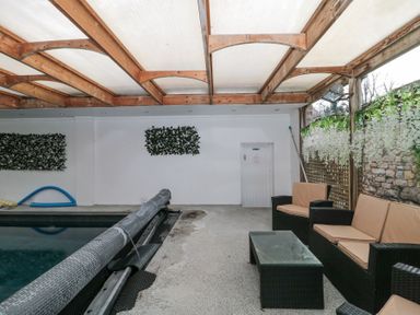 An indoor pool area with a covered pool and wicker seating furniture at Bell tent 2 in Camerton near Timsbury