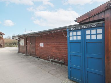 A blue police call box outside a wooden building with bike racks at Bell tent 2 in Camerton near Timsbury