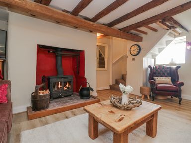A living room with a fireplace and armchair at High Ickenthwaite Farmhouse Ulverston