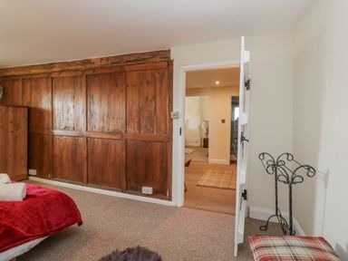 A bedroom with a wooden wardrobe and an open door at High Ickenthwaite Farmhouse in Ulverston