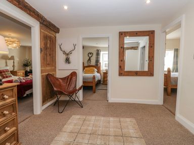 A hallway with a mirror and doors leading to rooms at High Ickenthwaite Farmhouse in Ulverston