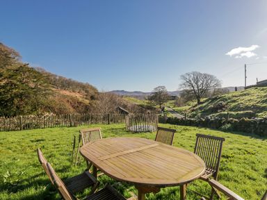 A garden with a wooden dining table and chairs at High Ickenthwaite Farmhouse Ulverston