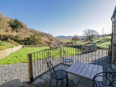 An outdoor area with table and chairs overlooking a landscape at High Ickenthwaite Farmhouse in Ulverston