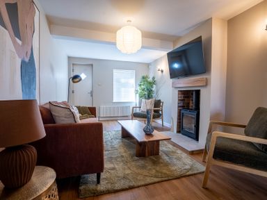 A living room with a sofa chairs coffee table rug and a fireplace with a mounted TV at Driftwood in Kessingland