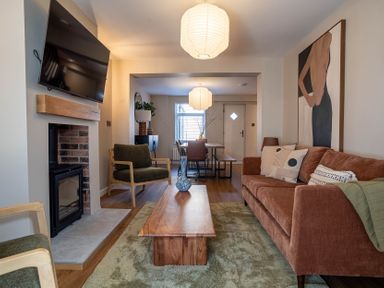 A living room with a sofa armchairs a coffee table and a fireplace with a tv above it at Driftwood in Kessingland