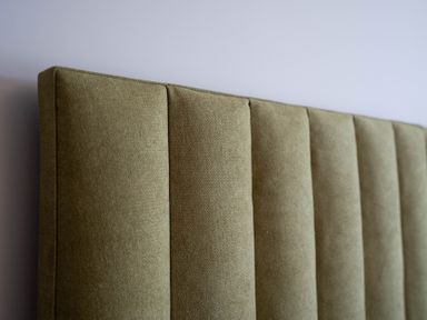 A close up of a beige padded headboard against a light-colored wall at Driftwood in Kessingland