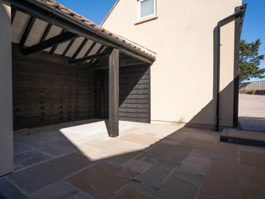 A covered outdoor area with wooden beams and tiled flooring at Driftwood in Kessingland