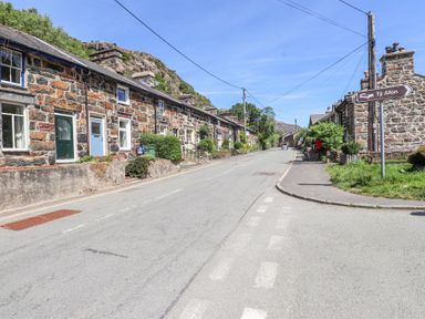 A street with stone houses and a road sign pointing to Ty Afon at Llys Emrys in Beddgelert