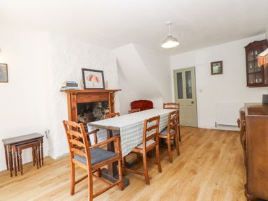 A dining room with wooden chairs around a table and a fireplace at Llys Emrys in Beddgelert