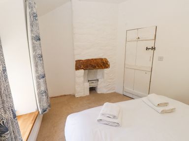 A bedroom with a bed with folded towels a small fireplace and a door at Llys Emrys in Beddgelert