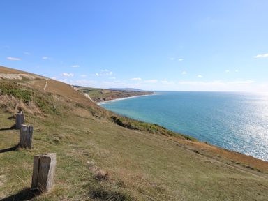 A coastal landscape with grassy hills and a blue sea under a clear sky at Plimoth N8 in Yarmouth