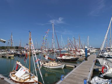 A marina with docked sailboats decorated with colorful flags at Plimoth N8 in Yarmouth