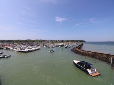 A marina with several boats docked and a boat moving in the water at Plimoth N8 in Yarmouth