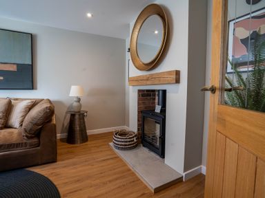 A living room with a sofa table lamp fireplace mirror and wooden door at The Reef in Kessingland