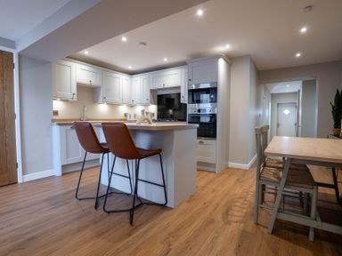 A kitchen area with an island and two chairs next to a dining table with three chairs at The Reef in Kessingland