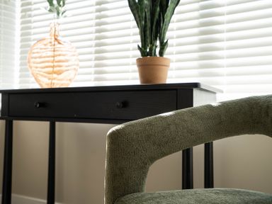 A black desk with drawers with a brown vase and a potted plant on it and a green chair in front at The Reef in Kessingland