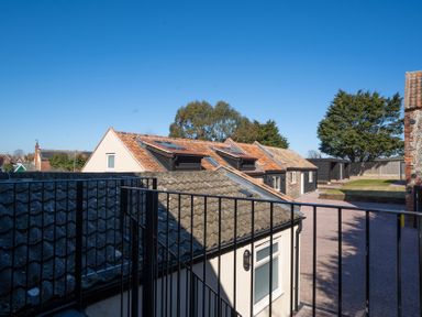 View of rooftops and a paved courtyard with trees and buildings in the background at The Cove in Kessingland