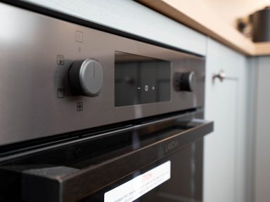 A close-up view of a built-in oven with control knobs and a digital display in a kitchen
