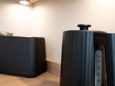 A close-up of a black electric kettle on a kitchen counter with a matching black toaster in the background at Coral Cottage in Kessingland