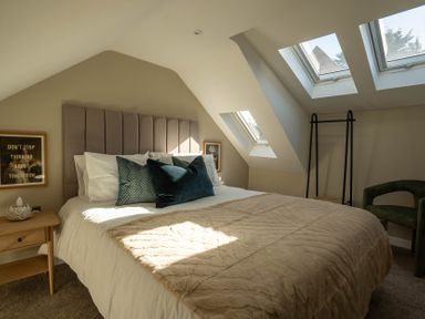 A bedroom with a bed pillows a bedside table framed picture and skylight windows at Coral Cottage in Kessingland