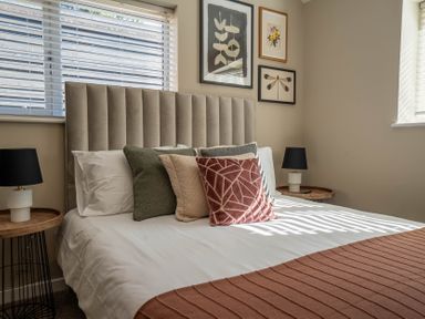 A bedroom with a bed with pillows and bedside tables with lamps at Dunes Cottage in Kessingland