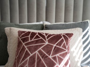 A close up of a bed with pillows including a patterned red pillow in front at Dunes Cottage in Kessingland