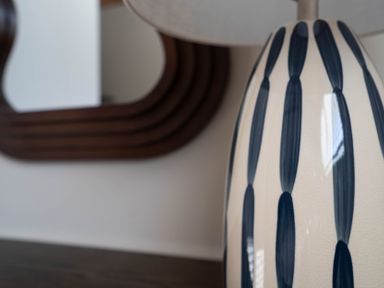 A close-up of a striped ceramic lamp with a brown framed mirror in the background at Dunes Cottage in Kessingland