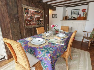 A dining room with a table set with plates chairs and a purple tablecloth at Cobblers Cottage in Langton Herring