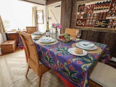 A dining room with a table set with plates glasses and food at Cobblers Cottage in Langton Herring