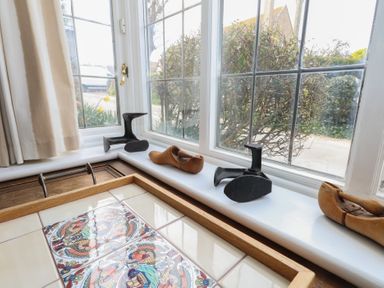 A windowsill with shoe lasts and metal shoe molds next to a table with decorated tiles at Cobblers Cottage in Langton Herring