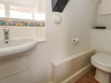 A bathroom with a sink and a toilet with tiled floor at Cobblers Cottage in Langton Herring