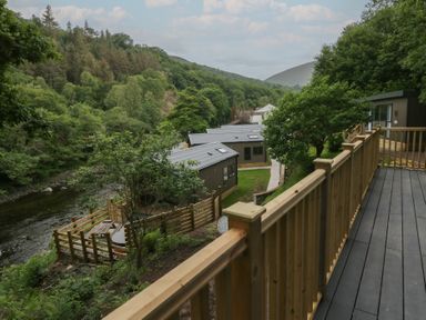 A view of cabins and a river surrounded by trees at Hodge Luxury Pod Keswick