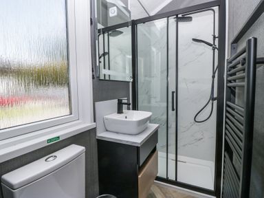 A bathroom with a toilet sink shower and heated towel rail at Woof Luxury Family Pod in Keswick