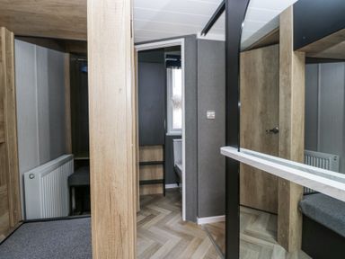 A room with wood panel walls a radiator a door a window and a bench at Woof Luxury Family Pod in Keswick