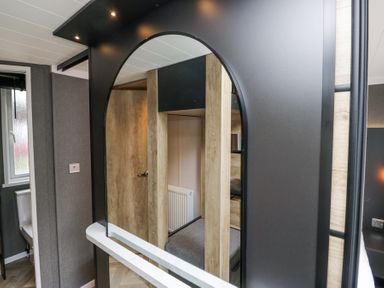 A bedroom with a bunk bed reflected in an arched mirror next to a bathroom at Woof Luxury Family Pod in Keswick