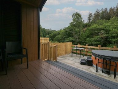 An outdoor area with a hot tub and table at Woof Luxury Family Pod in Keswick