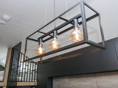 A black rectangular pendant light fixture with three exposed bulbs hanging from a ceiling at Lingy Luxury Family Pod in Keswick