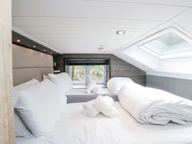 A bedroom with two beds pillows towels and a skylight window at Lingy Luxury Family Pod in Keswick