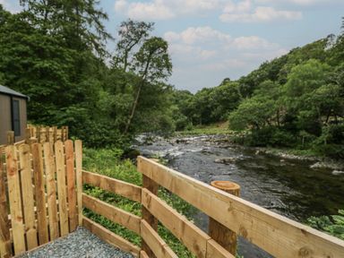 A river surrounded by trees and a wooden fence at Lingy Luxury Family Pod in Keswick