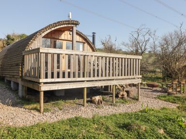 A wooden cabin with a deck and outdoor seating area with fire pit at Cabanau Bach in Bedwas