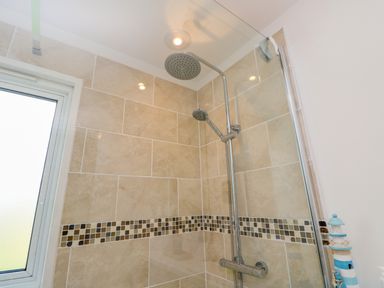 A tiled shower area with a rain shower head and handheld shower at Plimoth N9 in Yarmouth