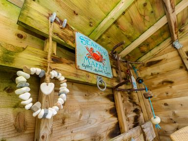 A wooden wall with a seafood market sign a heart shaped stone garland and hanging nautical decorations at Plimoth N9 in Yarmouth