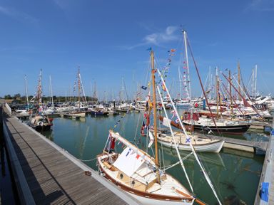 A marina with sailboats docked and decorated with flags at Plimoth N9 in Yarmouth