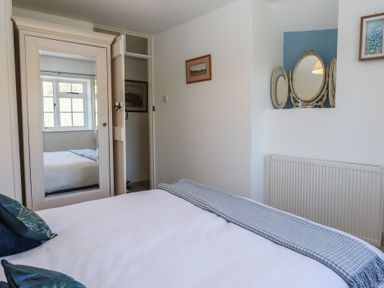 A bedroom with a bed, wardrobe with mirrored door, radiator, and a decorative mirror at Badger's Den in Budleigh Salterton